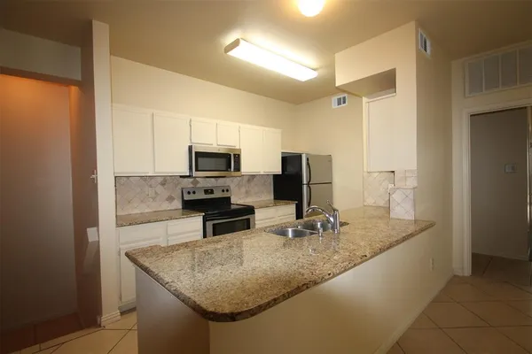 a kitchen with stainless steel appliances granite countertop a sink a microwave and refrigerator