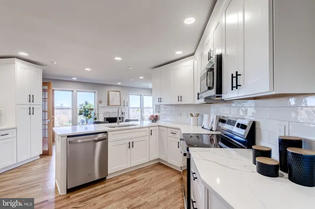 a kitchen with a sink dishwasher stove and white cabinets