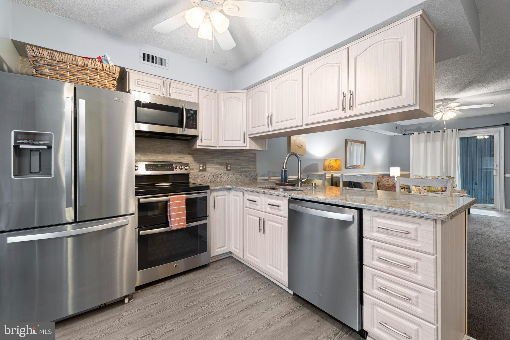 9815 Stephen Decatur Highway, Unit 14 Ocean City, MD 21842 - Photo 3 of 30 a kitchen with stainless steel appliances granite countertop a refrigerator stove a sink and dishwasher with wooden floor
