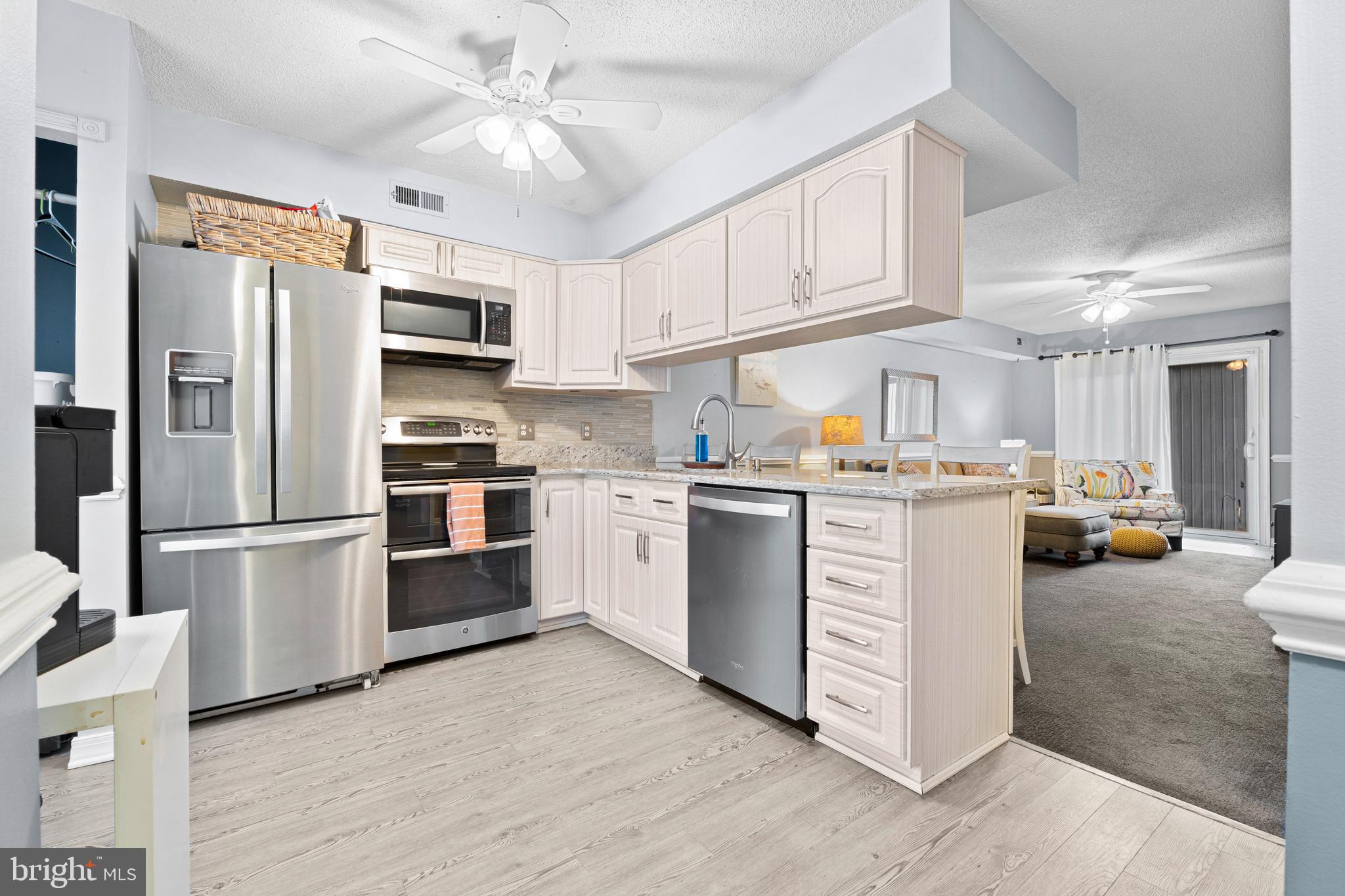 9815 Stephen Decatur Highway, Unit 14 Ocean City, MD 21842 - Photo 7 of 30 a kitchen with white cabinets and stainless steel appliances