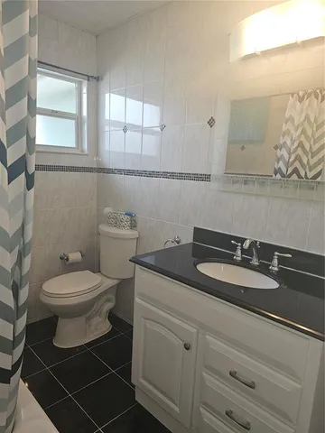 a bathroom with a granite countertop toilet sink and mirror