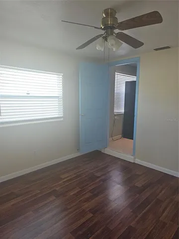 an empty room with wooden floor fan and windows