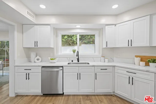 a kitchen with white cabinets sink and window