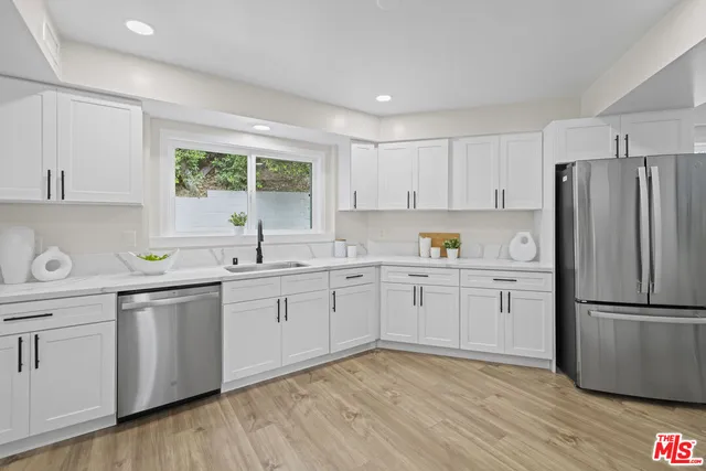 a kitchen with a refrigerator wooden floor a sink and a window