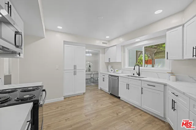 a kitchen with white cabinets and appliances