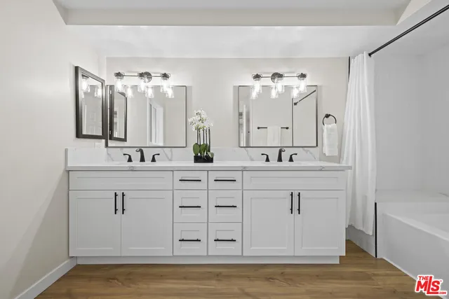 a bathroom with a double vanity sink mirror and bathtub