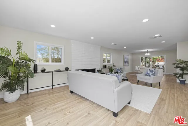 a living room with furniture a potted plant and kitchen view