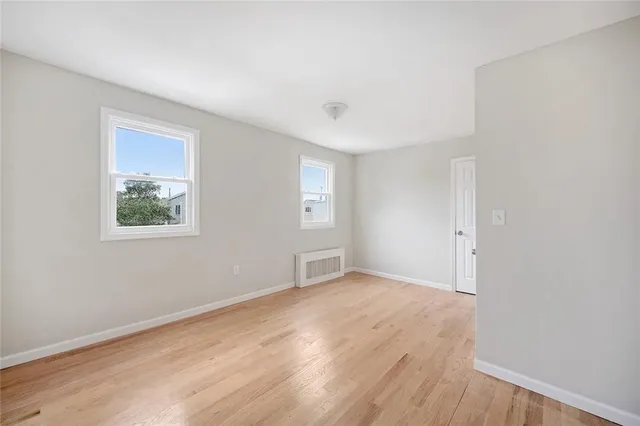 a view of an empty room with window and wooden floor