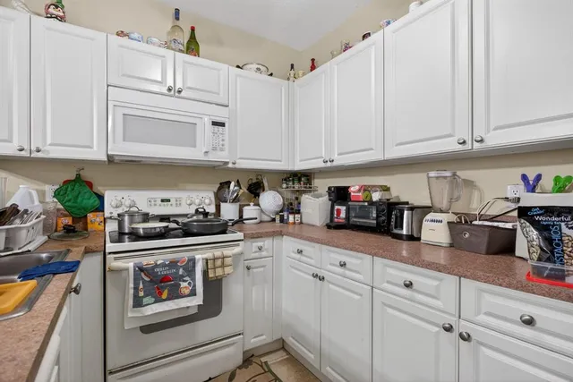 a kitchen with white cabinets and white appliances