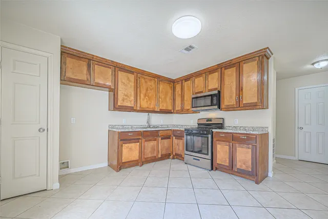 a kitchen with stainless steel appliances granite countertop a stove top oven a sink dishwasher and a refrigerator with wooden cabinets