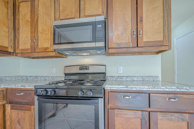a kitchen with granite countertop stainless steel appliances white cabinets granite counter tops and a wooden floors