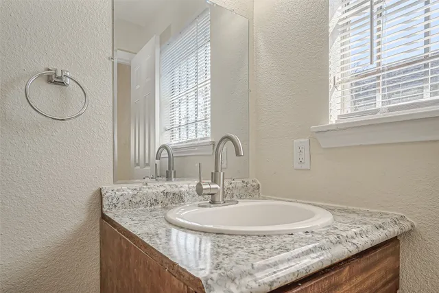 a bathroom with a granite countertop sink and a mirror