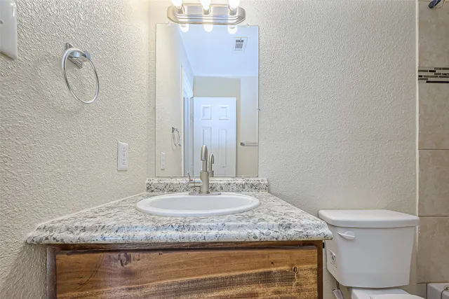 a bathroom with a granite countertop sink a toilet and mirror