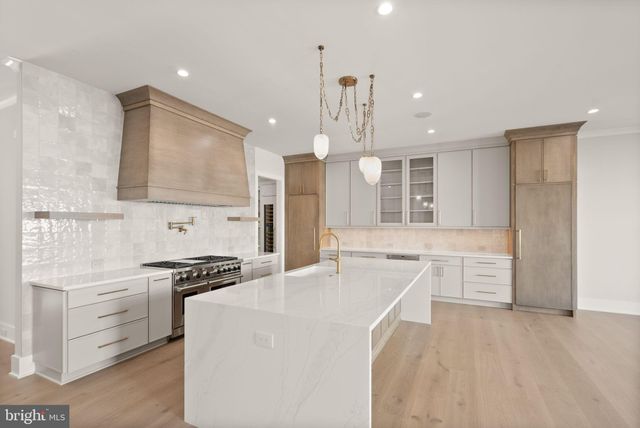 a large kitchen with stainless steel appliances a stove a sink dishwasher and a refrigerator with wooden floor