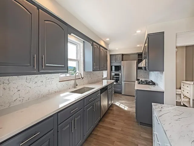 a kitchen with stainless steel appliances kitchen island granite countertop a sink stove and refrigerator