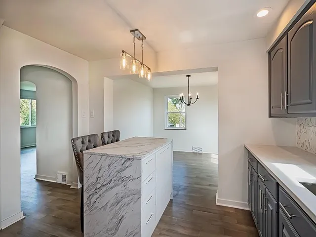 a kitchen that has a sink a microwave oven a stove and white cabinets with wooden floor