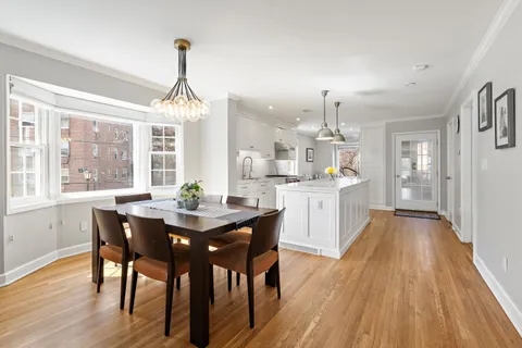 a dining room with wooden floor a chandelier a wooden table and chairs