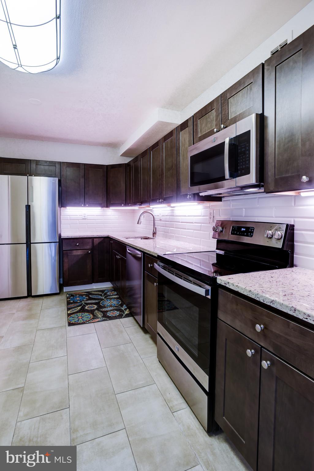 4100 Cathedral Avenue Northwest, Unit 512 Washington, DC 20016 - Photo 17 of 71 a kitchen with stainless steel appliances kitchen island granite countertop a stove and a microwave