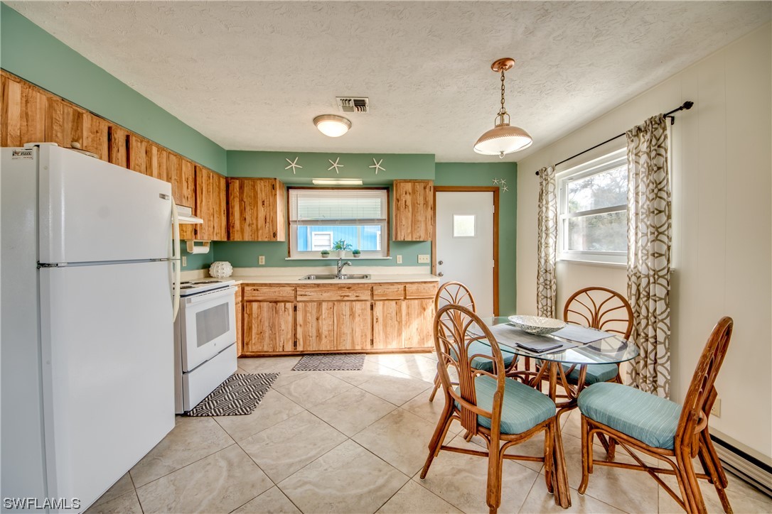 5892 Sailfish Road Bokeelia, FL 33922 - Photo 11 of 32 a kitchen with refrigerator a stove a sink and chairs