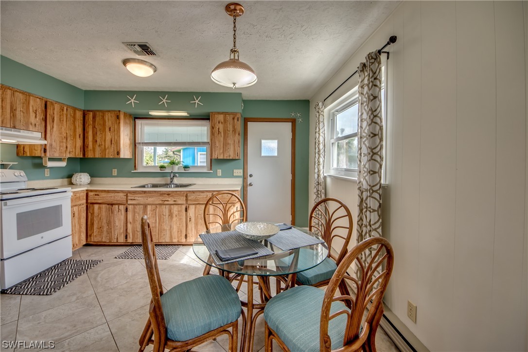 5892 Sailfish Road Bokeelia, FL 33922 - Photo 7 of 32 a kitchen with granite countertop a dining table chairs stove a sink and dishwasher