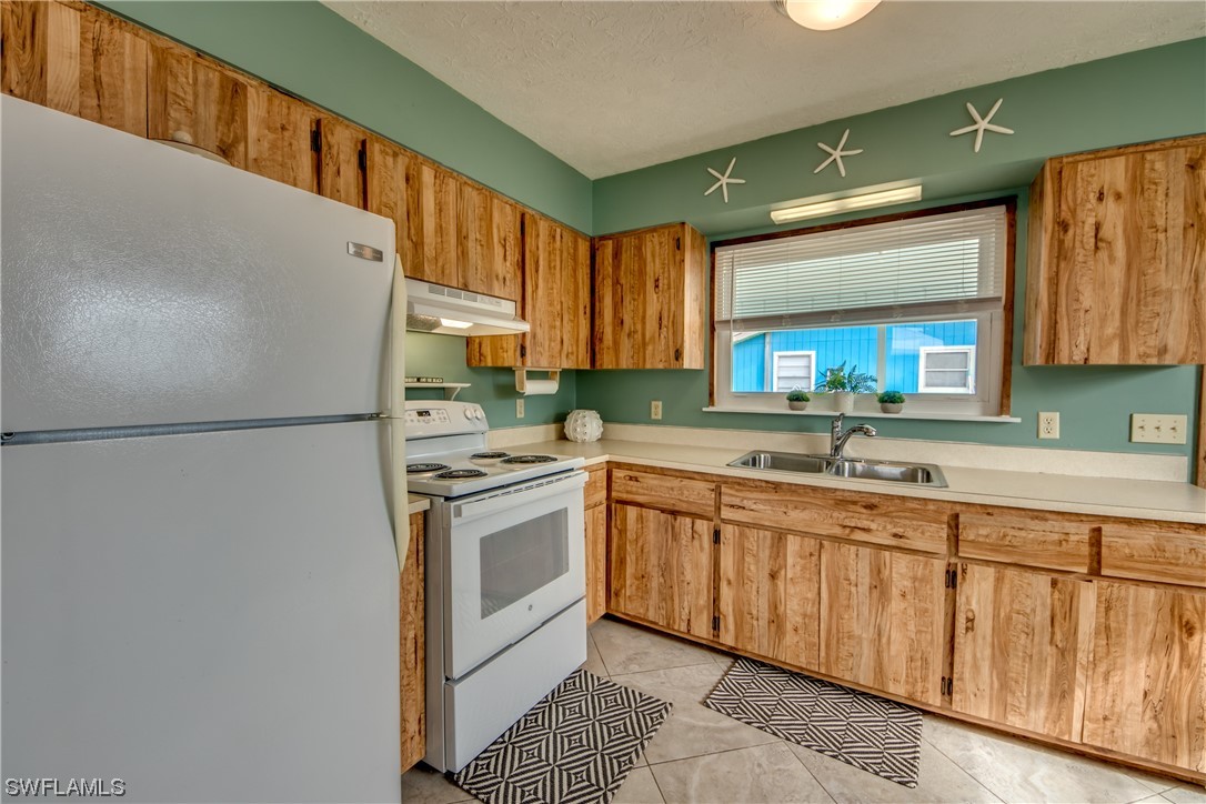 5892 Sailfish Road Bokeelia, FL 33922 - Photo 9 of 32 a kitchen with stainless steel appliances granite countertop a refrigerator a sink dishwasher a stove top oven a sink and dishwasher