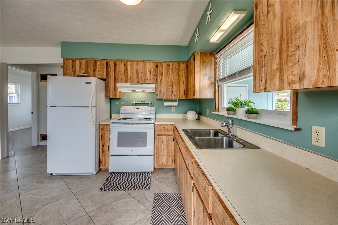 5892 Sailfish Road Bokeelia, FL 33922 - Photo 10 of 32 a kitchen with a refrigerator sink and cabinets