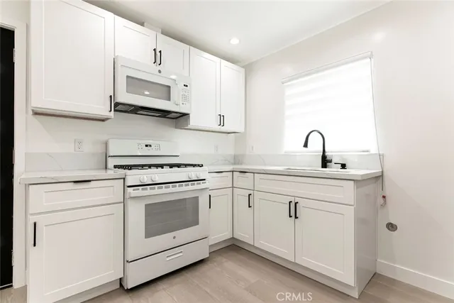 a kitchen with white cabinets stainless steel appliances and sink