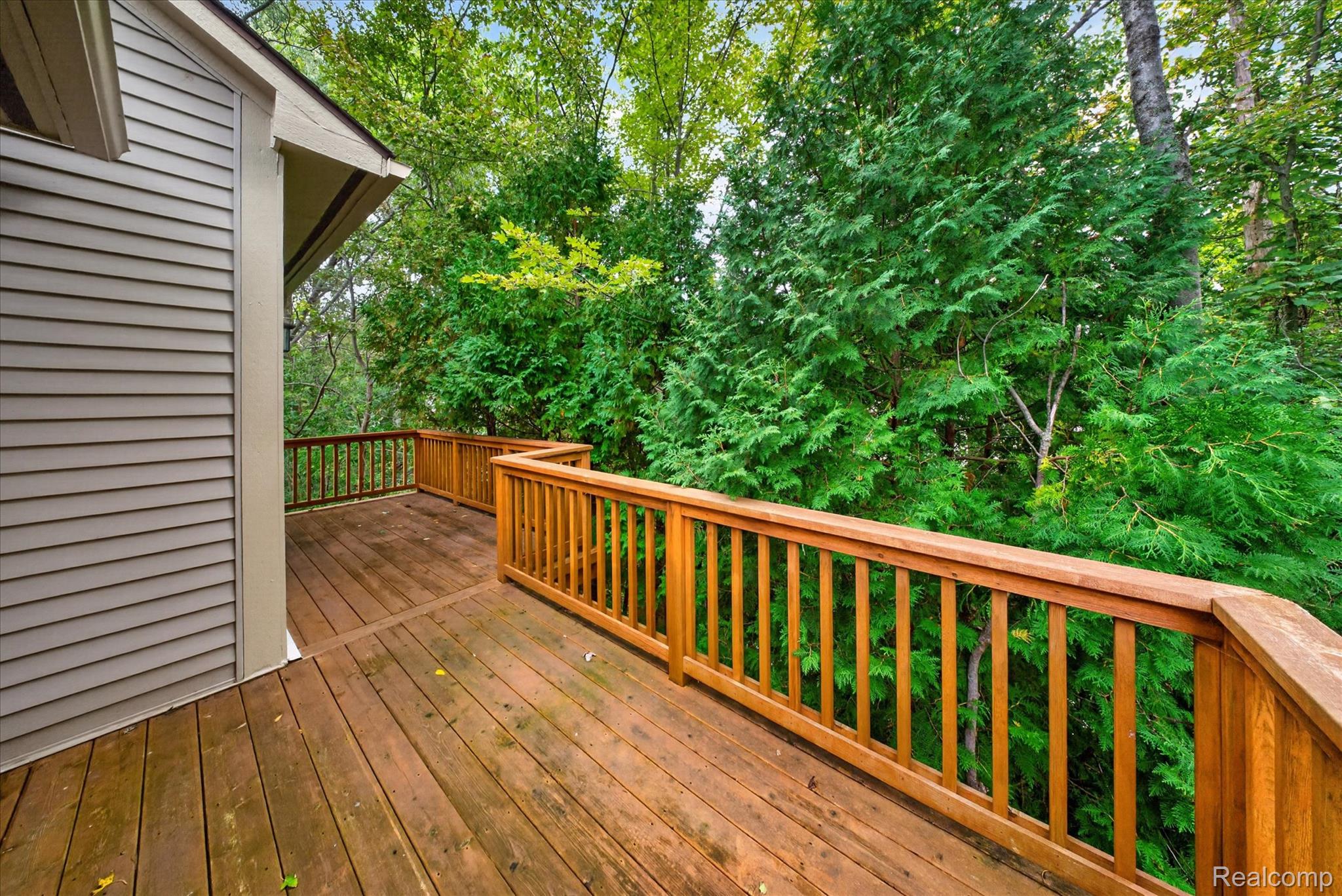 30900 Jasper Ridge Novi, MI 48377 - Photo 38 of 45 Wood deck with natural wood railings, bordered by natural landscaping and mature trees