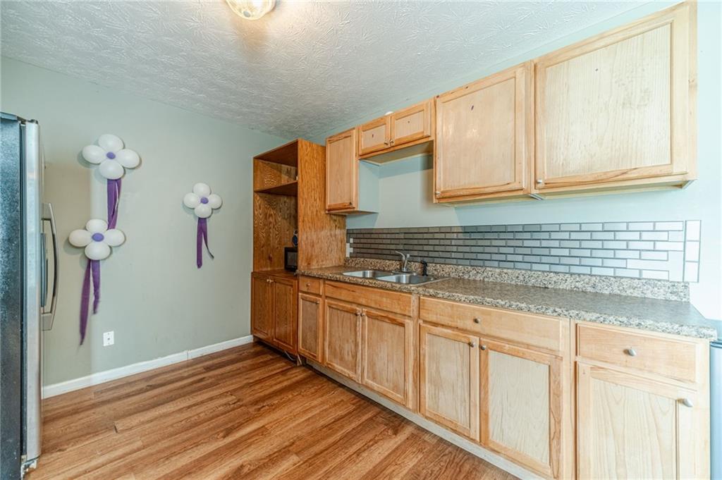 1185 Wendy Way Winder, GA 30680 - Photo 39 of 46 a kitchen with stainless steel appliances granite countertop a sink and cabinets with wooden floor