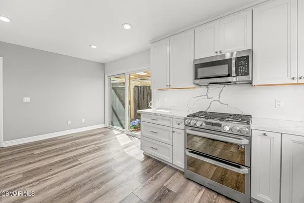 a kitchen with stainless steel appliances white cabinets and a stove top oven