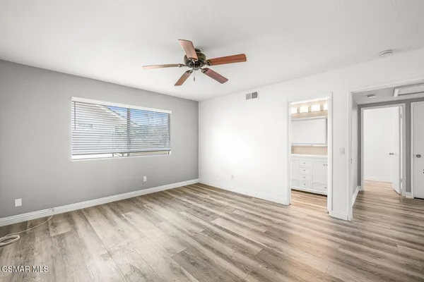 a view of empty room with wooden floor and fan