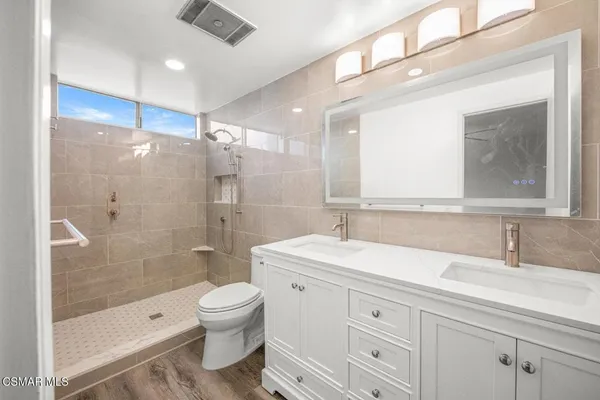 a bathroom with a toilet a shower a sink and mirror