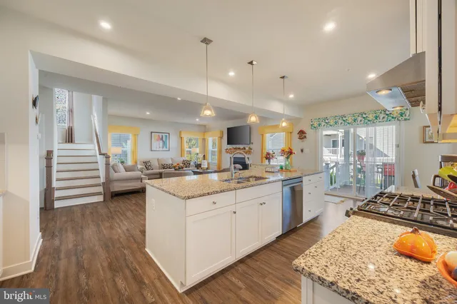 a large kitchen with stainless steel appliances granite countertop a lot of counter space and wooden floors