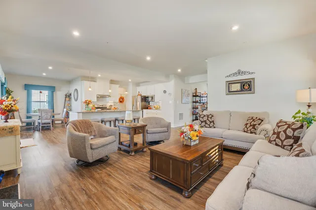 a living room with furniture kitchen view and a wooden floor