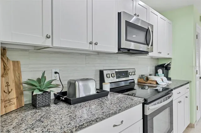 a kitchen with stainless steel appliances granite countertop a sink a stove and a microwave