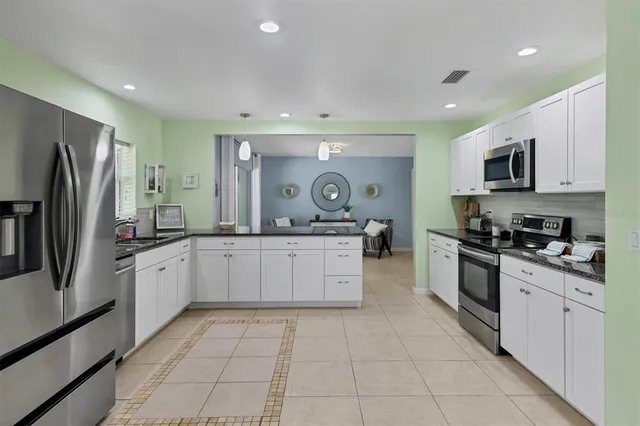 a large kitchen with stainless steel appliances granite countertop a large stove top oven a refrigerator a sink and dishwasher