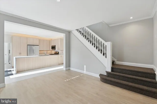 a view of empty room with wooden floor and kitchen view