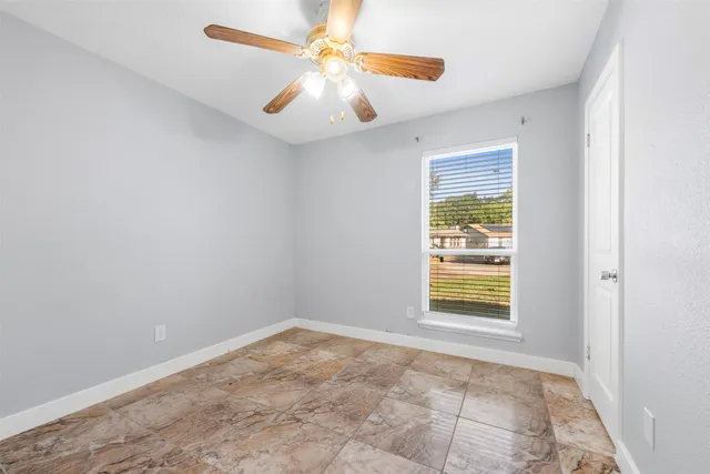an empty room with windows and fan