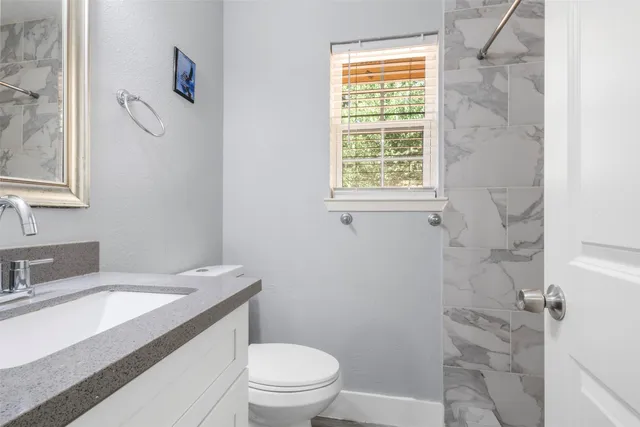 a bathroom with a granite countertop sink toilet a mirror and shower