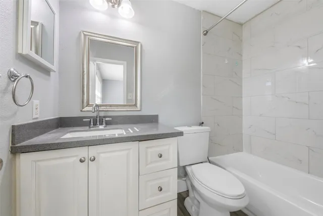 a bathroom with a granite countertop toilet sink and mirror