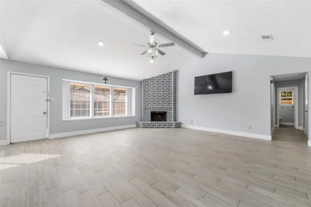 a view of an empty room with a fireplace and a window
