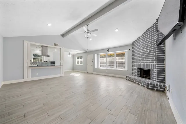 a view of an empty room with a window and fireplace