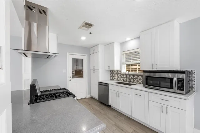 a kitchen with stainless steel appliances a stove a microwave and white cabinets