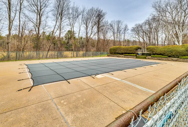 a swimming pool that has lawn chairs under an umbrella