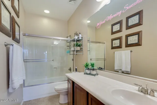 a bathroom with a granite countertop shower sink vanity mirror and toilet