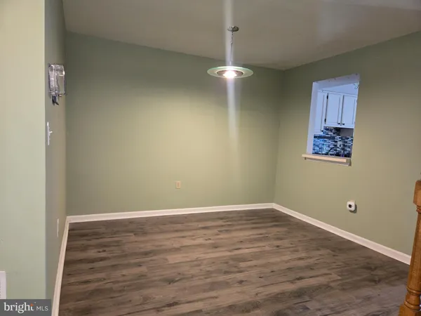 an empty room with wooden floor and chandelier