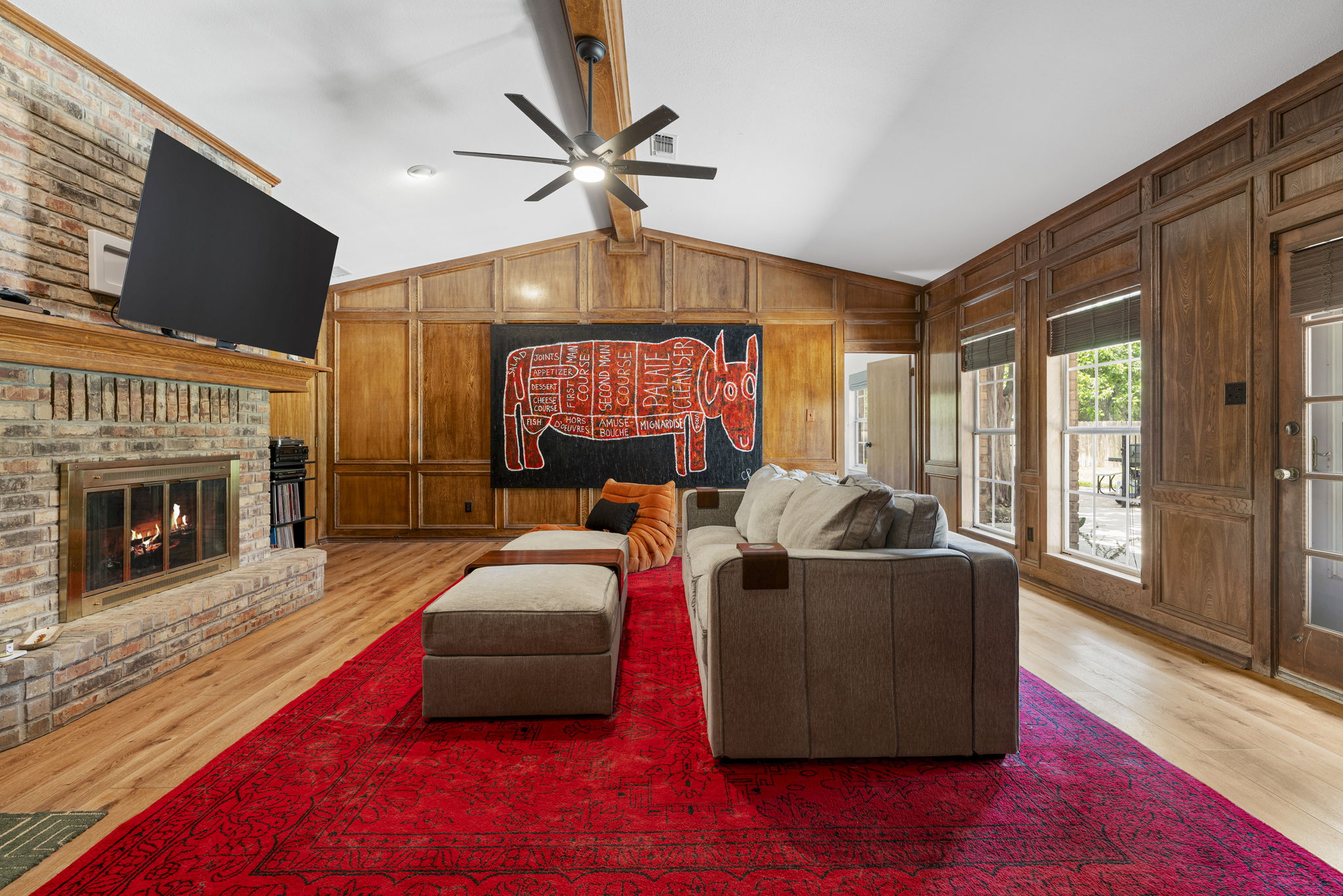 400 Hackberry Street Lockhart, TX 78644 - Photo 7 of 40 A striking brick fireplace grounds this spacious living area with warm wood paneling and ample natural light.