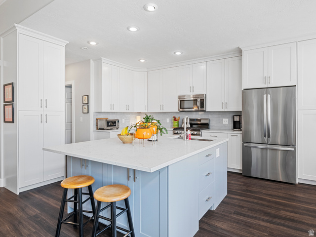 11881 Cottage View Lane Draper, UT 84020 - Photo 4 of 29 Contemporary kitchen featuring a light blue island with a bright countertop, stainless steel appliances, white cabinetry, recessed lighting, and wood-finish flooring