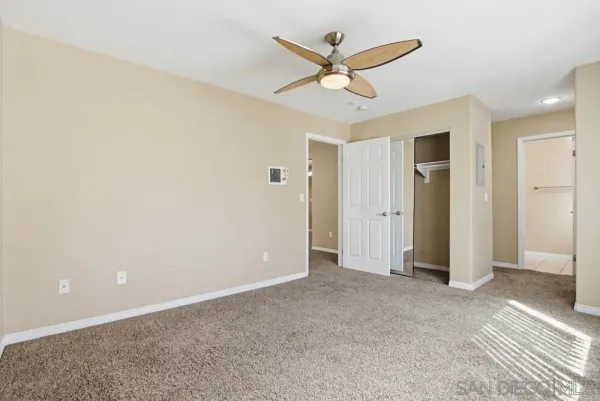 an empty room with closet and a ceiling fan