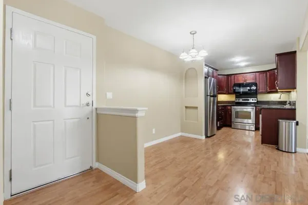 an open kitchen with wooden floor and a refrigerator
